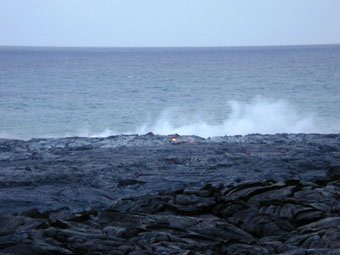 Lava flow toward the ocean with steam